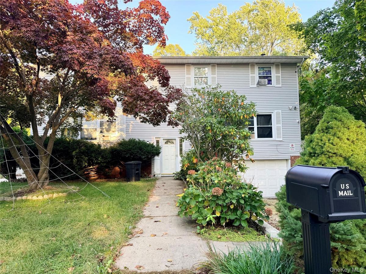 Two-story exterior featuring horizontal siding, a front-facing attached garage, white-trimmed windows with shutters, and a central entryway with a con