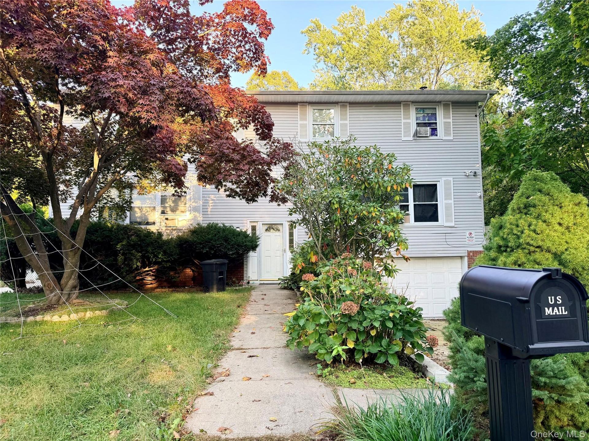 Two-story exterior featuring horizontal siding, a front-facing attached garage, white-trimmed windows with shutters, and a central entryway with a con