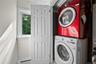 Utility space featuring stacked appliances, a single-hung window with casing, and a four-panel interior door
