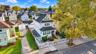 Three-story residence featuring a covered front porch, white siding, a paved driveway, and a fenced front yard with mature landscaping
