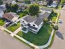 Corner lot property featuring two-tone exterior siding, stone veneer base, shingled roof, concrete driveway, and a paved walkway