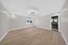 Spacious room featuring wide-plank wood-finish flooring, a multi-arm modern light fixture, and recessed lighting