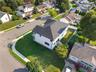 Corner lot featuring a multi-level structure with a gabled roof, white siding, and a fenced rear perimeter