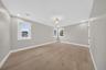 Neutral-toned interior featuring wood-finish flooring, recessed lighting, a modern ceiling fixture, and multiple windows with white trim