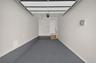 Finished garage featuring an epoxy-coated floor, overhead door mechanism, neutral wall paint, and an elevated entry door with interior steps