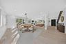 Open-concept living space featuring wood-finish flooring, recessed lighting, a geometric metal-frame chandelier, and a staircase with a black iron rai