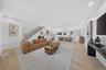 Open-concept living space featuring wood-finish flooring, recessed lighting, and a staircase with an iron-baluster railing