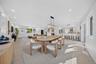 Open-concept area featuring recessed ceiling lighting, wood-finish flooring, a kitchen island with stone countertops, and a rectangular metal pendant 