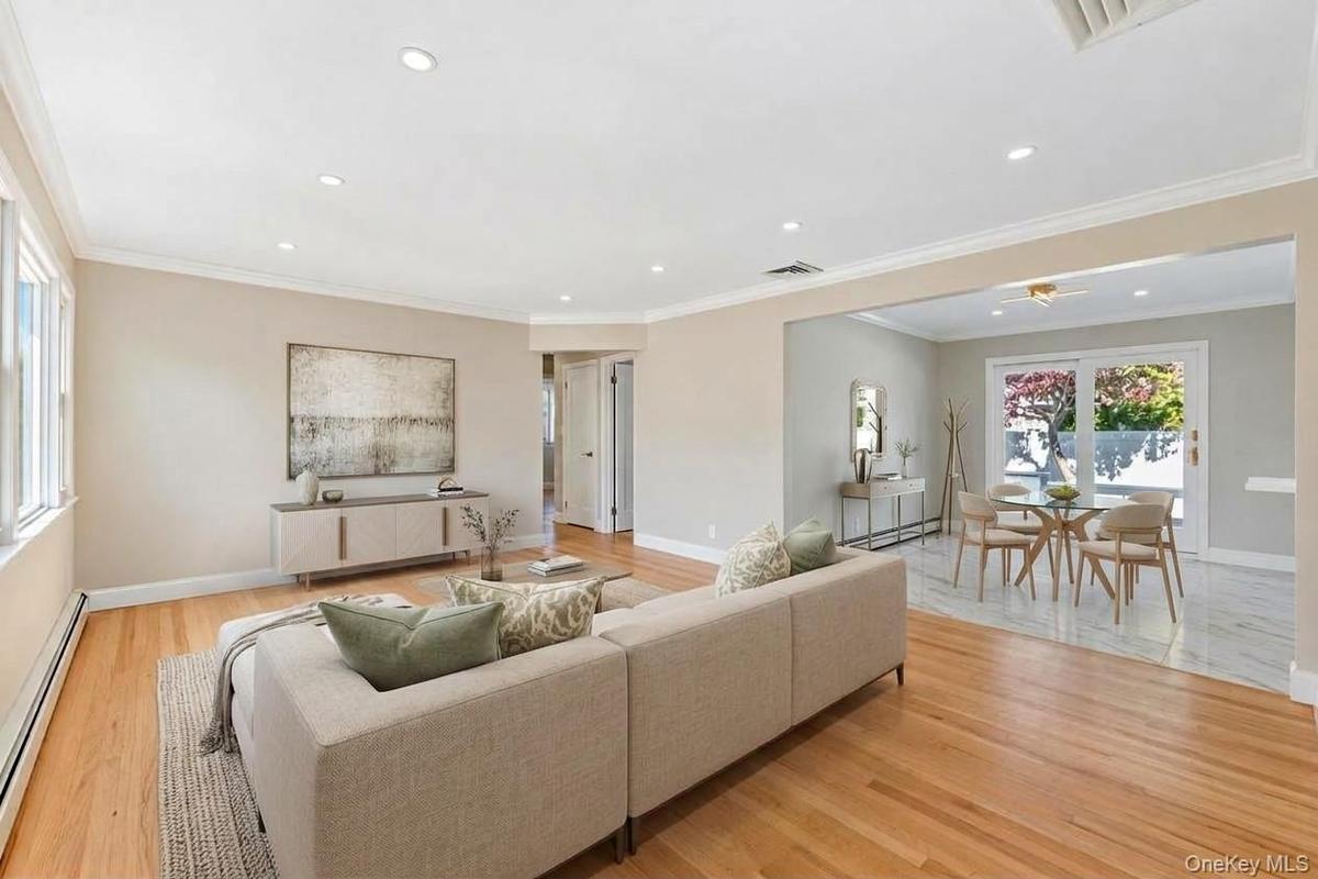 Open-concept interior featuring wood-finish flooring, recessed lighting, crown molding, and glass sliding doors