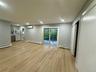 Open-concept interior featuring light wood-finish flooring, recessed lighting, sliding glass door, wall-mounted climate control unit, and closet with 