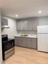 Kitchen featuring gray shaker-style cabinetry, solid-surface countertops, recessed lighting, and wood-finish flooring