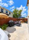Fenced backyard featuring a concrete patio, perimeter wood fencing, and overhead string lighting