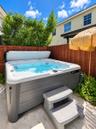 Exterior spa with a gray composite finish, integrated stairs, and a wood privacy fence