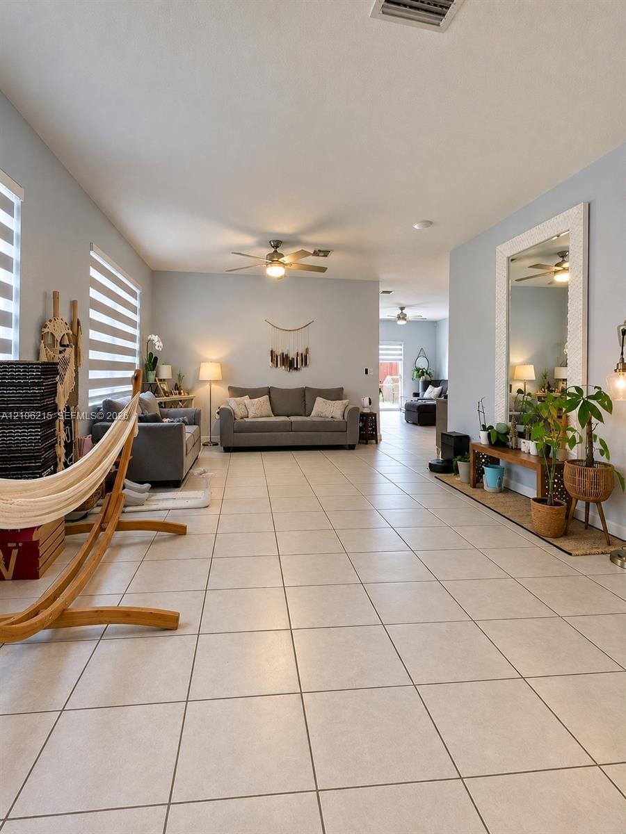 Neutral-toned ceramic tile flooring, ceiling fans, and dual-layered window shades