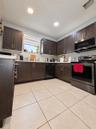 Kitchen featuring dark-finish cabinetry, solid-surface countertops, large-format tile flooring, and stainless steel appliances including a built-in mi