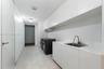 Utility space featuring expansive white cabinetry, white countertop, undermount stainless steel sink with a high-arch faucet, and large-format tile fl