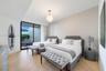 Room featuring wood-finish flooring, textured wall covering, floor-to-ceiling glass sliding doors, and a spherical pendant light fixture