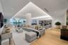 Open-concept living space featuring wood-finish flooring, recessed tray ceiling with integrated perimeter lighting, floor-to-ceiling windows, and rece