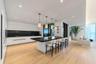Modern kitchen featuring flat-panel cabinetry, a central island with a solid surface countertop, wood-finish flooring, recessed lighting, and four cyl