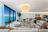 Floor-to-ceiling glass windows, tiered crystal chandelier, cove lighting, and wood-finish flooring