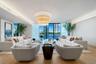Open-concept living space featuring wood-finish flooring, recessed perimeter ceiling lighting, a tiered drum chandelier, and expansive floor-to-ceilin