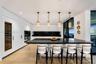 Sleek kitchen featuring flat-panel cabinetry, a spacious center island with a dark countertop, integrated wine refrigeration, built-in wall ovens, and