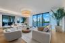 Living area featuring floor-to-ceiling glass walls, wood-finish flooring, multi-tier circular chandelier, and recessed lighting