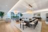 Open-concept living space featuring wood-finish flooring, recessed perimeter ceiling lighting, floor-to-ceiling windows, and dual statement chandelier