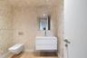 Floating white vanity with a rectangular sink, wall-mounted dual-flush toilet, large frameless mirror, wood-finish flooring, and metallic patterned wa