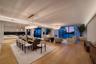 Open-concept interior featuring wood-finish flooring, recessed LED cove lighting, floor-to-ceiling glass windows, contemporary pendant lighting, and f