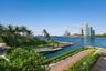 Waterfront property featuring a private boat dock, extensive paved driveway, manicured landscaping, and coastal scenery