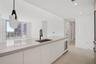 Kitchen island featuring a stone countertop, undermount sink with a matte black faucet, built-in under-counter beverage chiller, and modern pendant li