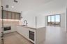 Modern kitchen featuring white flat-panel cabinetry, light-toned stone countertops, a waterfall-edge island, built-in wine refrigeration, and a matte 