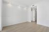 Neutral interior space featuring wood-finish flooring, recessed ceiling lighting, and a solid-core interior door with matte black hardware