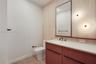 Powder room featuring a fluted wood vanity, integrated white countertop, wall-mounted matte black faucet, vertical textured wall tiling, and dual circ