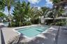 Swimming pool featuring stepped entry, paved deck, and mature palm landscaping