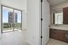 Floor-to-ceiling sliding glass door, private balcony, wood-finish flooring, floating vanity with dual-toned cabinetry, and large rectangular wall mirr
