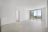 Open-concept interior featuring large-format tile flooring, recessed lighting, and floor-to-ceiling sliding glass doors opening to a balcony