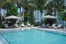 Swimming pool with integrated entry steps, concrete pool deck, and mature landscaping featuring palm trees
