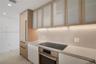 Custom cabinetry featuring light wood finish and reeded glass upper cabinet doors, integrated refrigeration, stone-finish countertops, and an inductio
