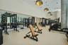 High-ceiling fitness center featuring expansive wall-to-wall mirrors, industrial-style dome pendant lighting, and concrete-finish support columns