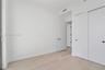 Room interior featuring light-toned wood-finish flooring, white walls, and a sliding-door closet with circular hardware