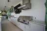 Outdoor kitchen featuring dual stainless steel ventilation hoods, built-in stainless steel grill, integrated sink with gooseneck faucet, and white cab