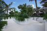 Landscaped grounds featuring curved white masonry planters, stone-finish paving, mature palm trees, and dense greenery
