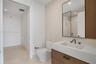 Floating wood-finish vanity with a stone countertop, rectangular undermount sink, matte black widespread faucet, and matching framed mirror, complemen
