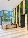 Floor-to-ceiling windows, vertical green plant wall, recessed lighting, and large-format tile flooring