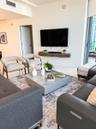 Living area featuring large-format tile flooring, recessed ceiling lighting, and a wall-mounted floating media console