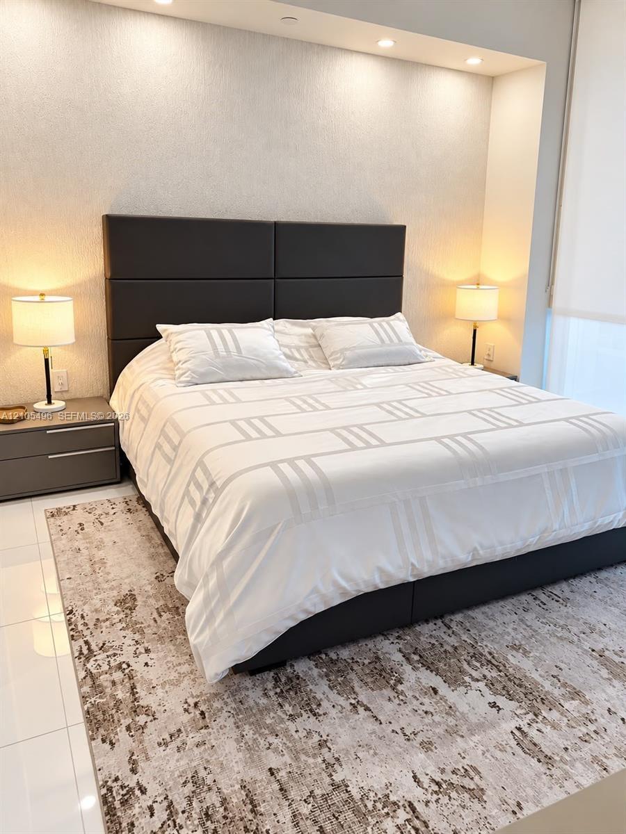Recessed ceiling lighting, textured wall finish, and glossy tile flooring