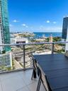 Private balcony featuring large-format tile flooring and a glass railing, showcasing expansive cityscape and water scenery