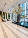 Double-height lobby featuring floor-to-ceiling glass walls, an indoor reflecting pool, a central ornamental tree, and a vertical green wall installati